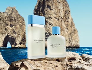 Dolce & Gabbana Light Blue Parfümflaschen für Damen und Herren auf Felsen vor dem blauen Meer und den ikonischen Faraglioni-Felsen in Capri.