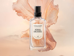 L'Occitane Néroli Orchidée Eau de Toilette – Flakon vor zarter rosafarbener Blüte und Pastellhintergrund