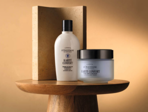 L'Occitane Karité Confort Körperlotion und Körpercreme auf Holztisch vor goldfarbenem Hintergrund