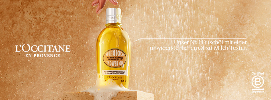 L'OCCITANE Duschöl in einer Flasche mit goldener Flüssigkeit auf einem sandigen Hintergrund.